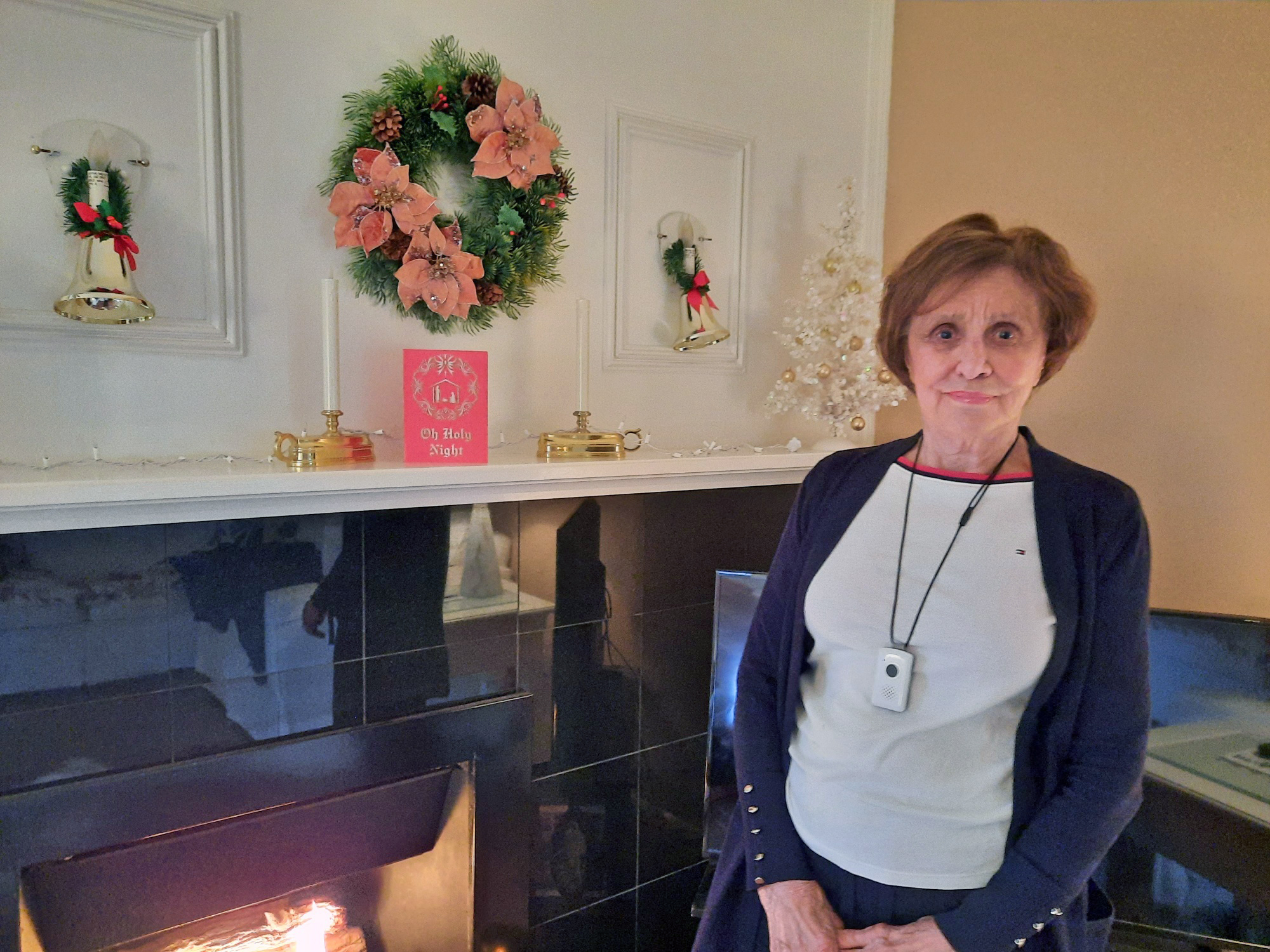 LifeLink user, Dolly stands in front of her fireplace in her condo, wearing her LifeLik unit.
