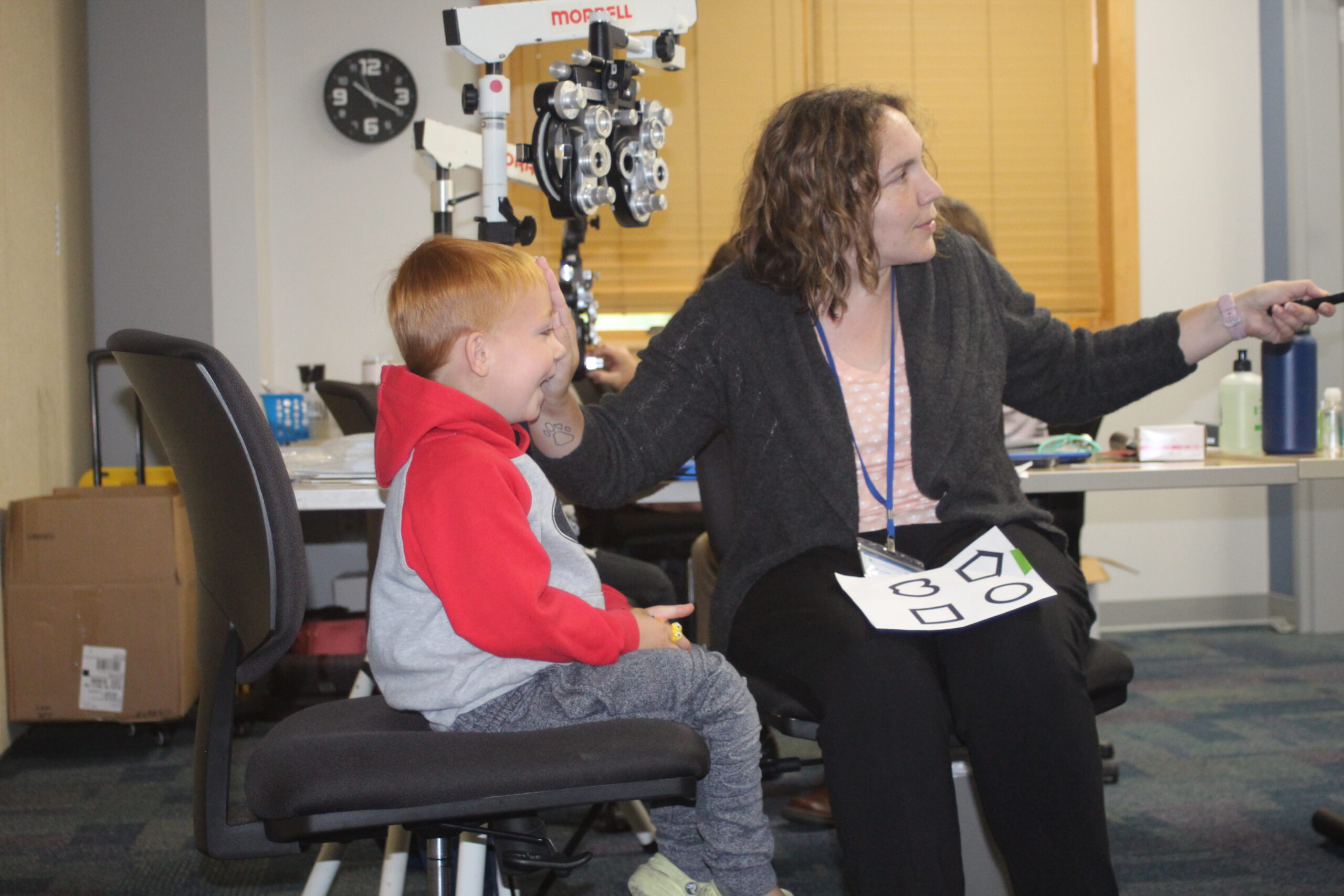 A young boy gets a Vision check by a an adult female at Tools for School