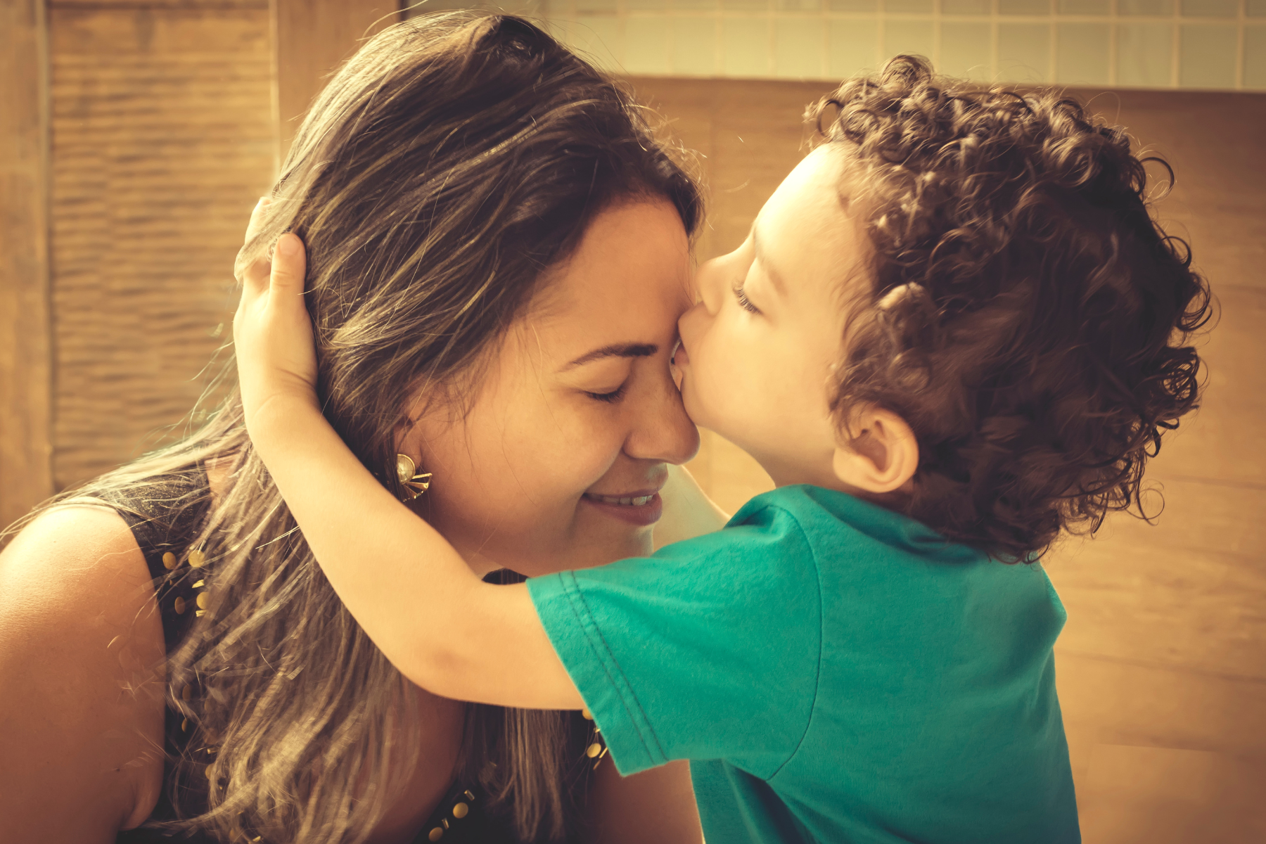 Young family. a young boy kisses his mother on the forehead.