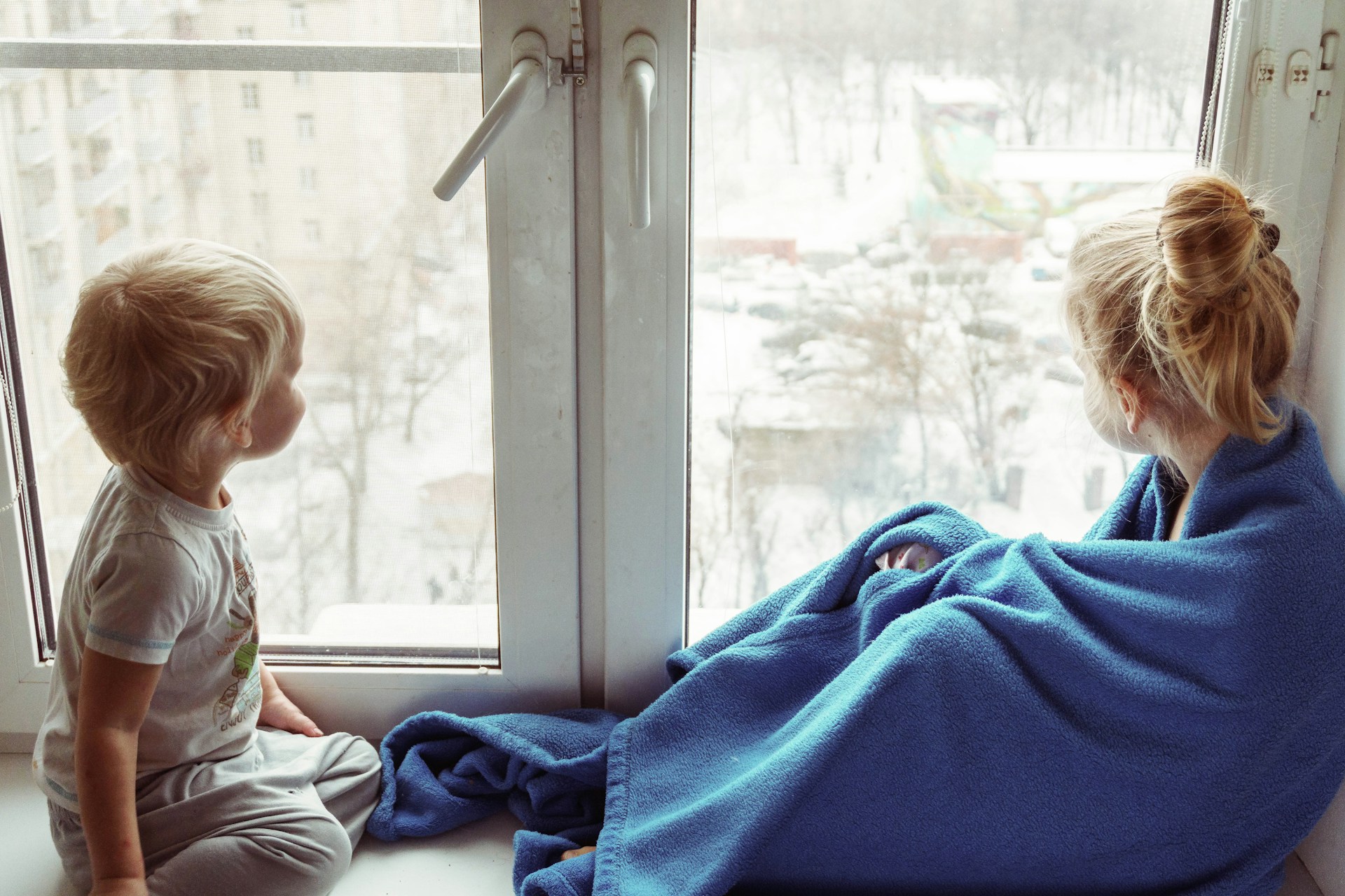 A young boy and girl looking out of a window in a family experiencing energy poverty.