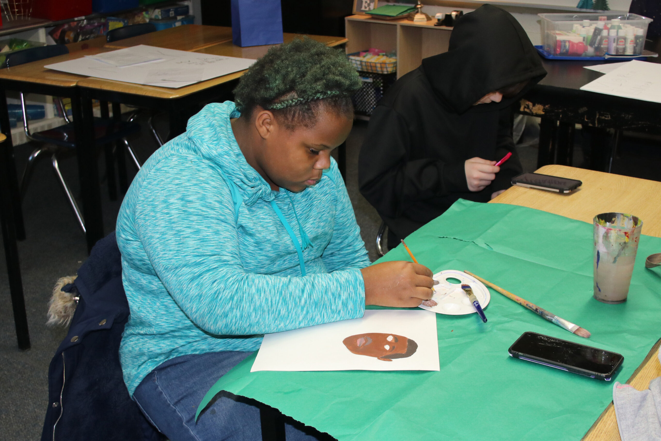 An African-American student working on a painting of Dr. Martin Luther King Jr. for an art project celebrating MLK Jr.