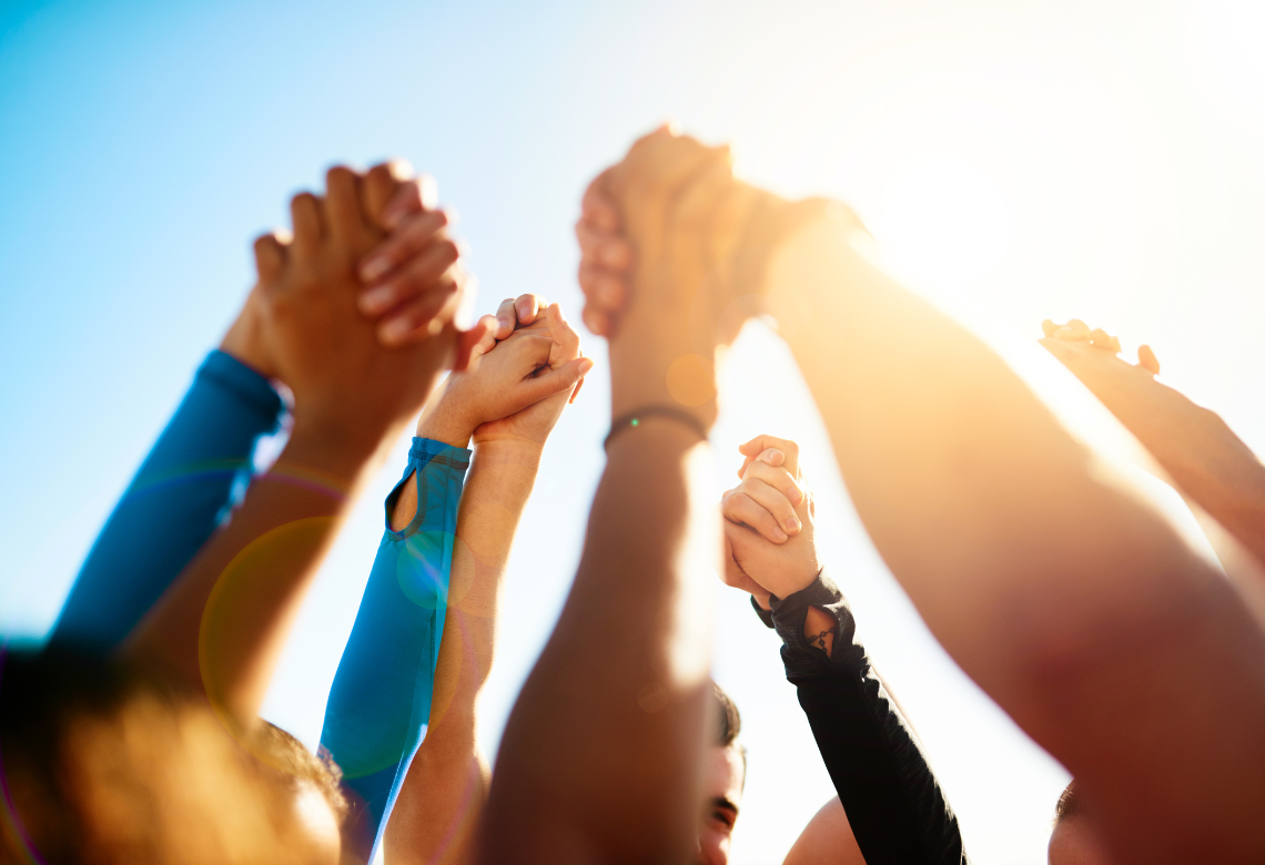 People holding hands with each other in the air, representing nonprofit membership programs.