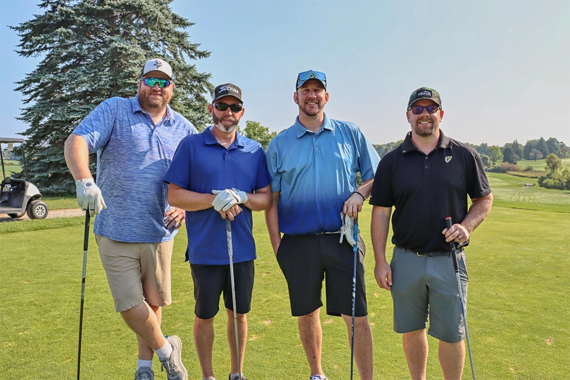 4 men in polo shirts and shorts holding golf clubs at the 2024 Tee Up for TrueNorth Golf Outing