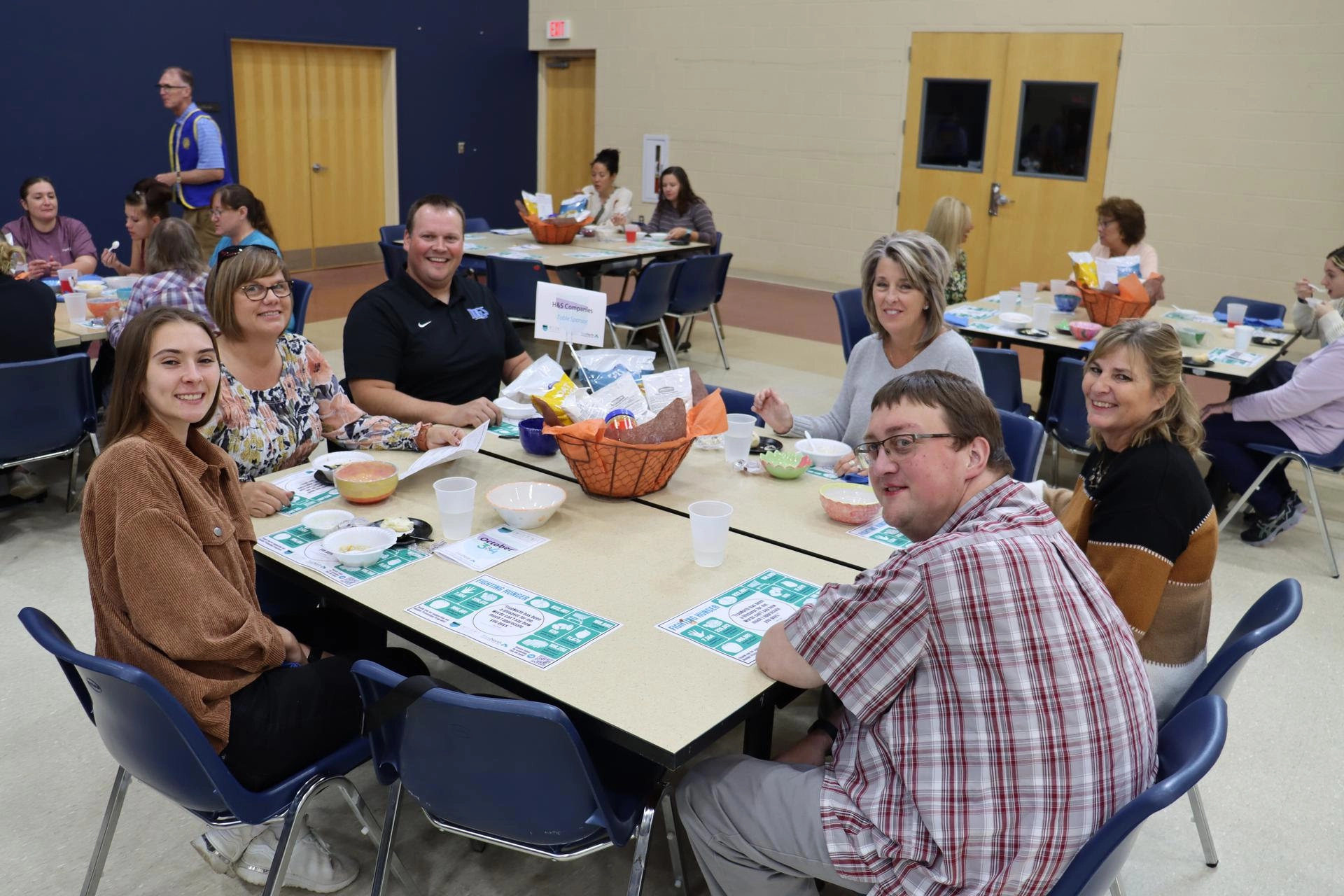 Six people smiling, sitting around a table at the 2024 Empty Bowls event