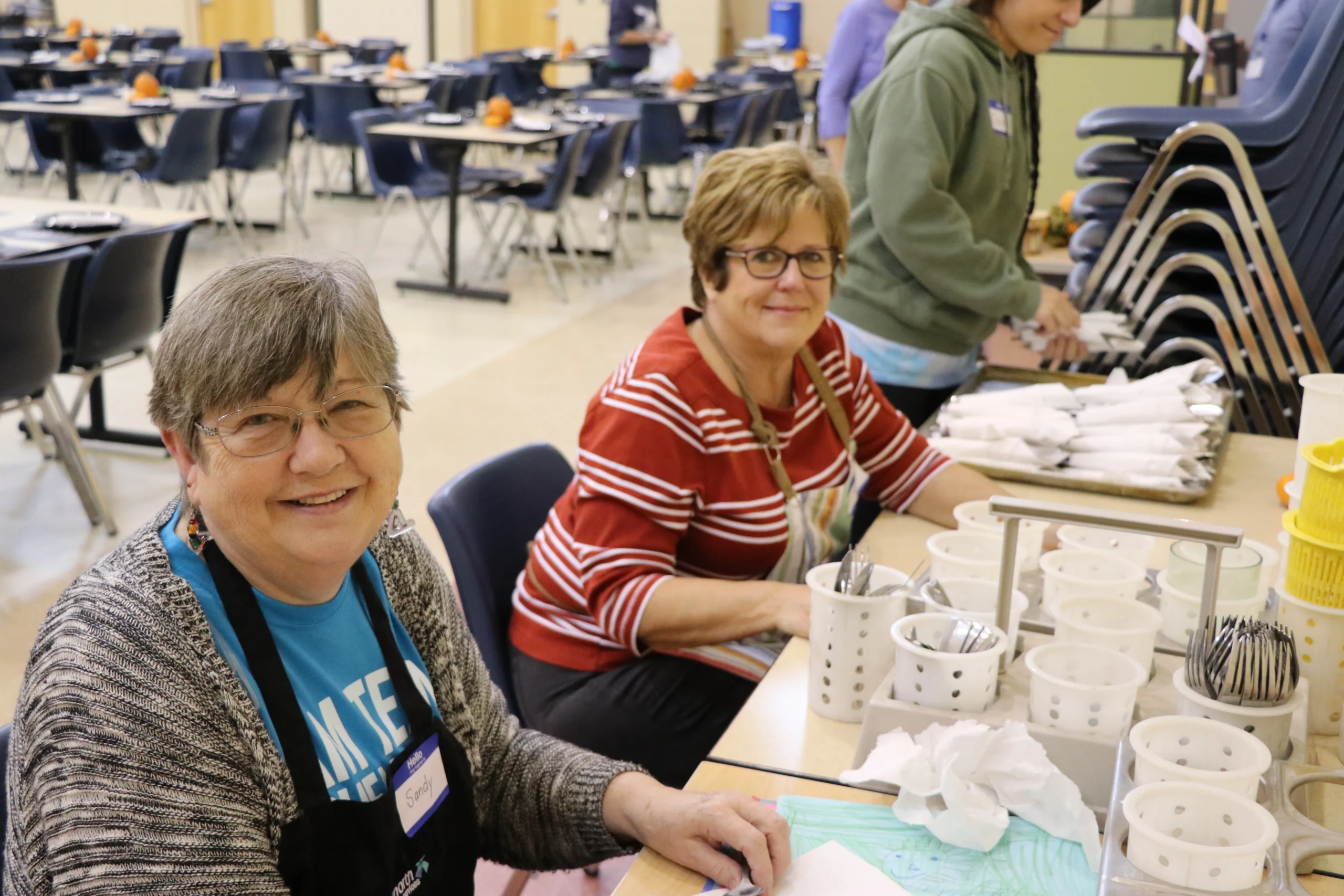 Two female volunteers, preparing silverware for an event