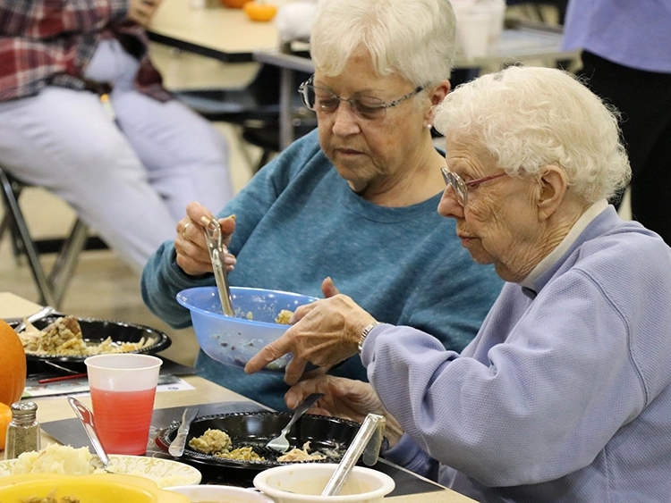 Two senior women are enjoying Thanksgiving dinner.