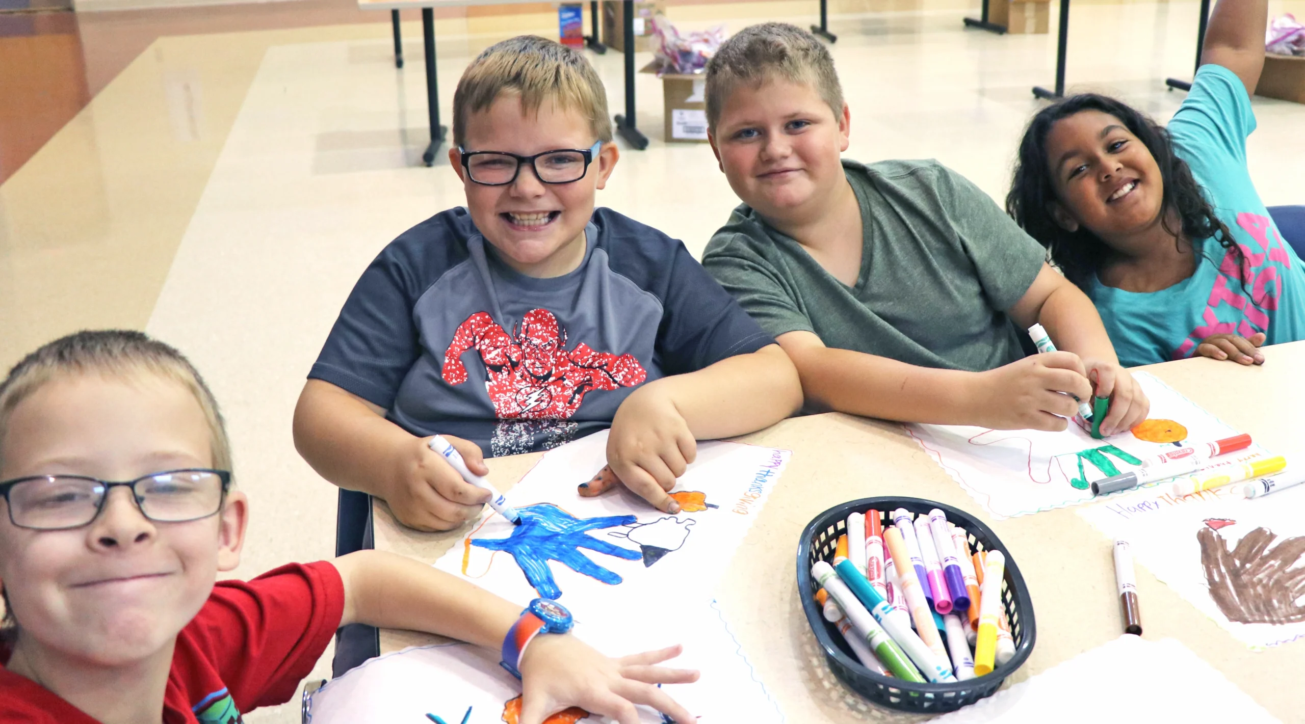 Four children sitting at a table doing a craft