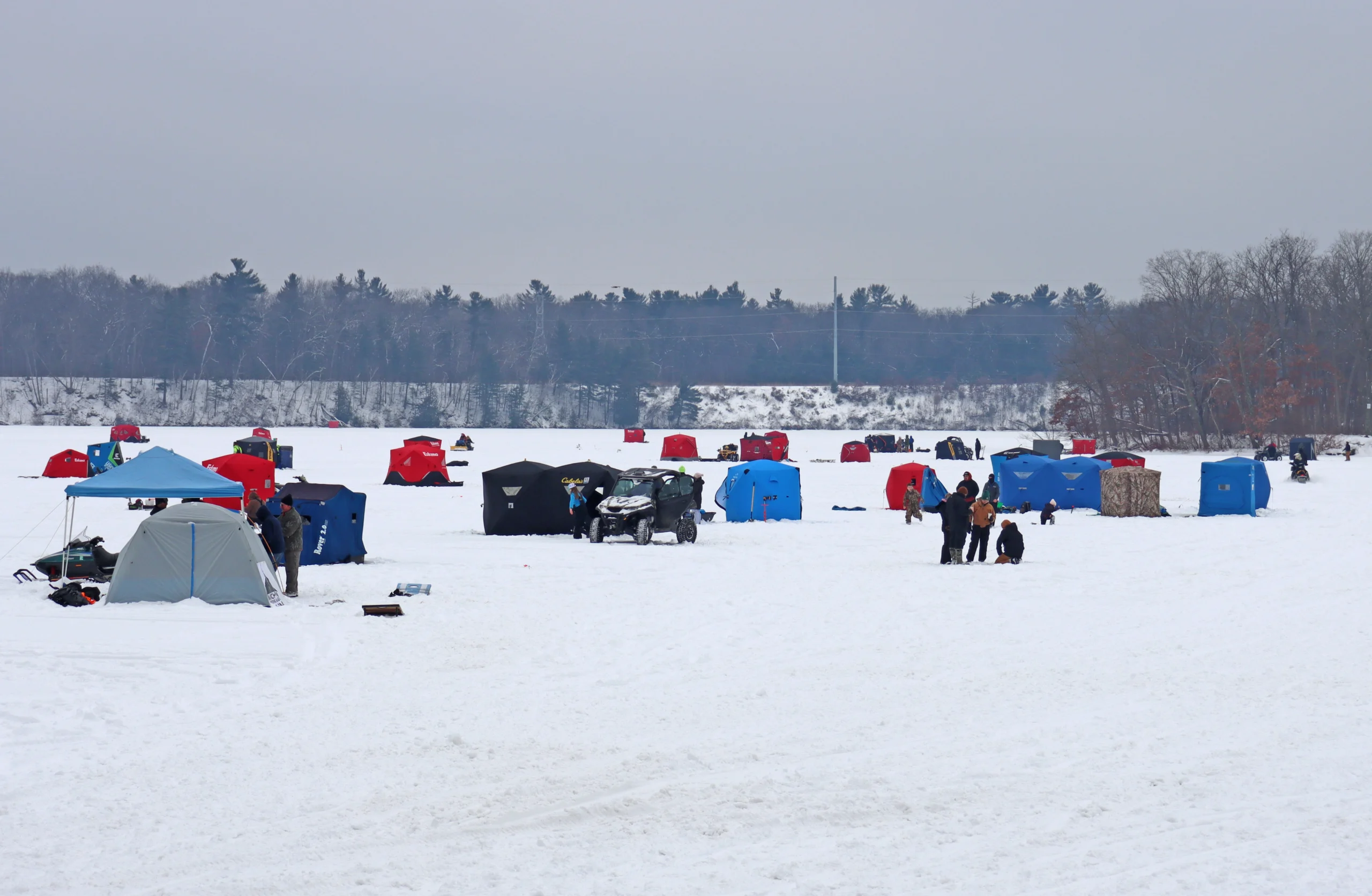many ice fishing shanties and tents dot the ice at Dam to Dam 2025