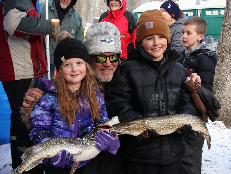 Two young kids holding fish.