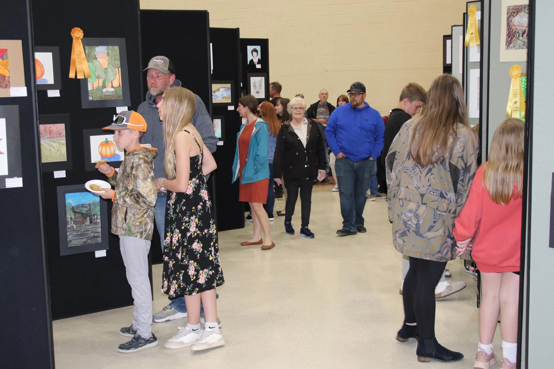 Several people walking through and the viewing student artwork