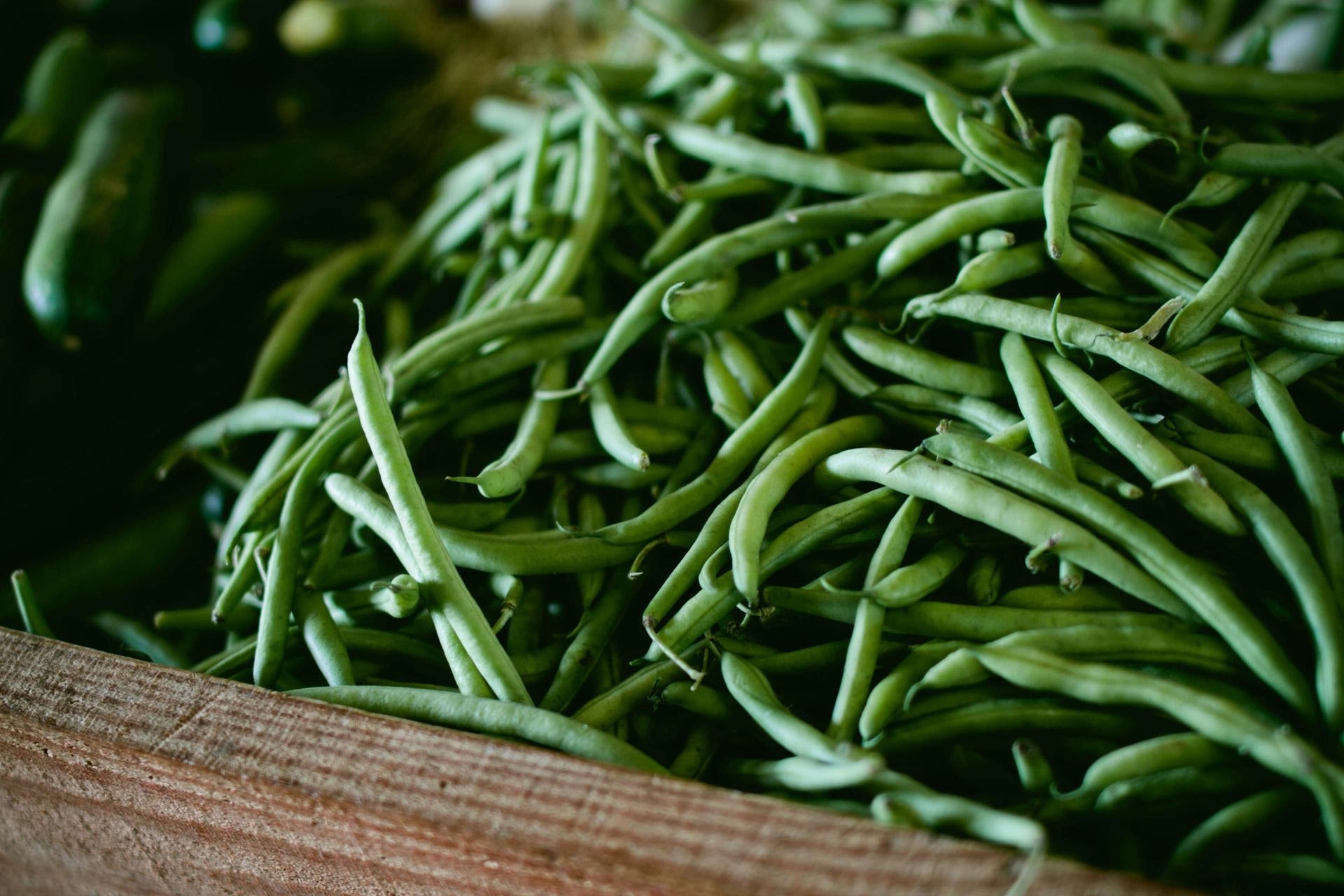 A large bundle of fresh green beans in a wooden box