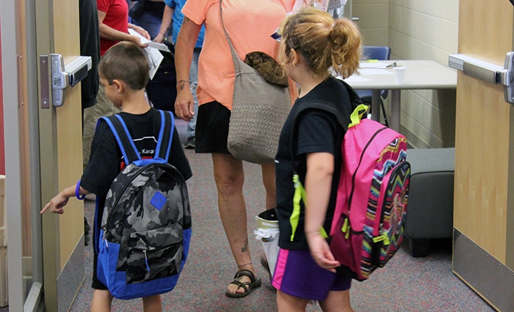 A boy and a girl displaying their new backpacks from Tools for School