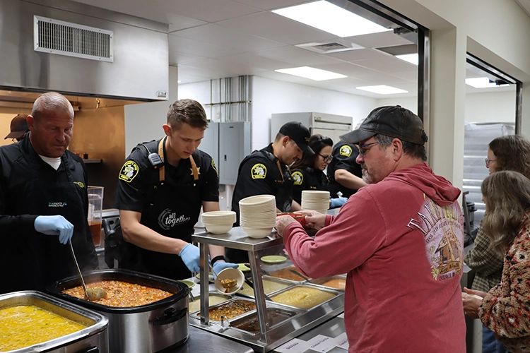 Local police help serve soup to participant at Empty Bowls soup luncheon